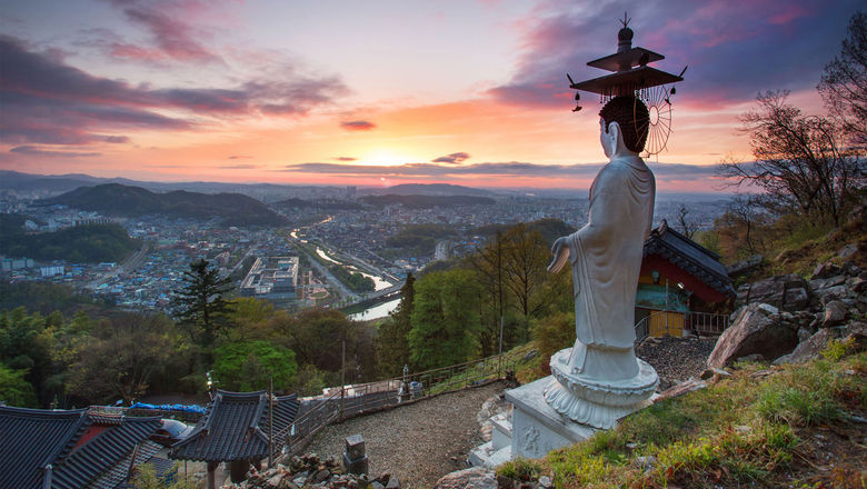 A statue towers over a buddhist temple in South Korea, a new destination Contiki offered in 2024.