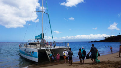 Guests line up and take turns boarding the catamaran, being careful to time it with the waves.