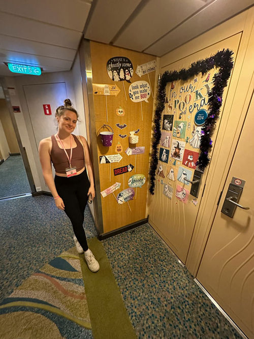 Emma Weissmann stands next to a decorated stateroom door on Allure of the Seas.