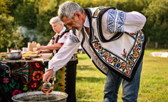 A man in folkloric costume cooks traditional food outdoors in Neamt County, Romania. Romania will become part of Europe's Schengen Area in January.